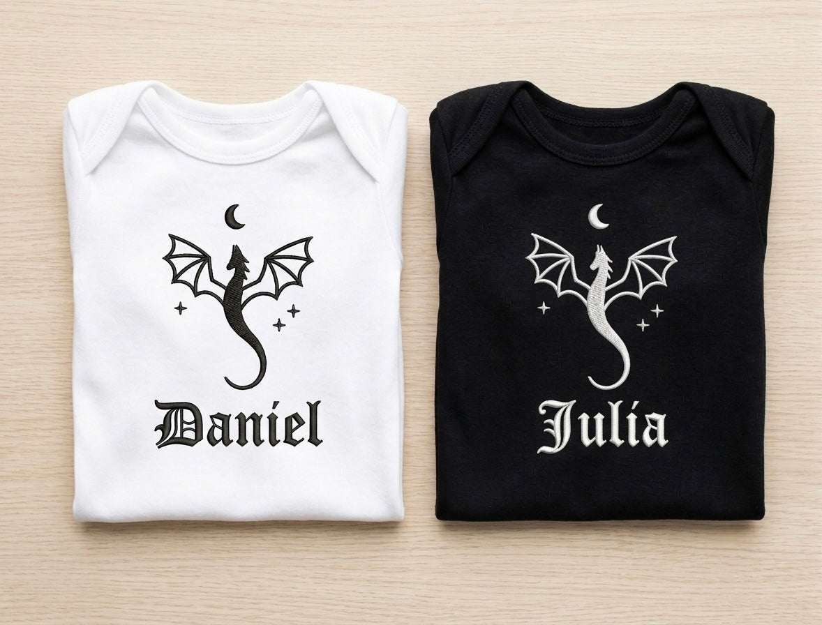 Two folded shirts, one white and one black, with dragon designs and names 'Daniel' and 'Julia' on a light wooden surface.
