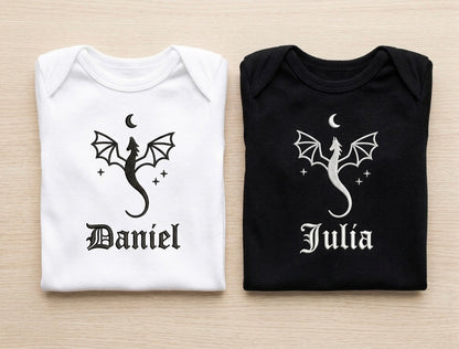 Two folded shirts, one white and one black, with dragon designs and names 'Daniel' and 'Julia' on a light wooden surface.