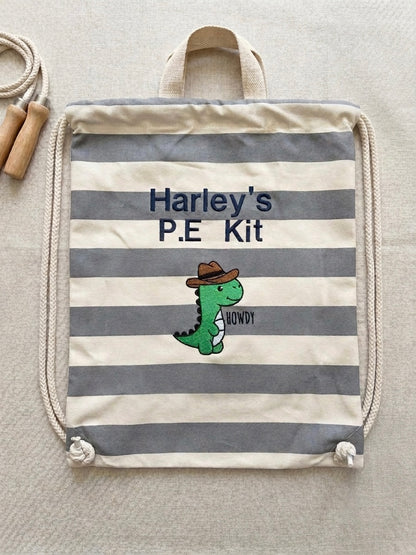 A striped canvas P.E kit bag with grey and cream horizontal stripes, featuring an embroidered green cartoon dinosaur wearing a brown hat and personalised embroidered name 