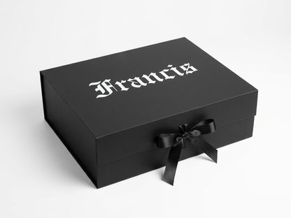 A black rectangular presentation box with the name 'Francis' printed in a white gothic font on the lid and a black ribbon tied in a bow on the front, photographed on a light gray background.