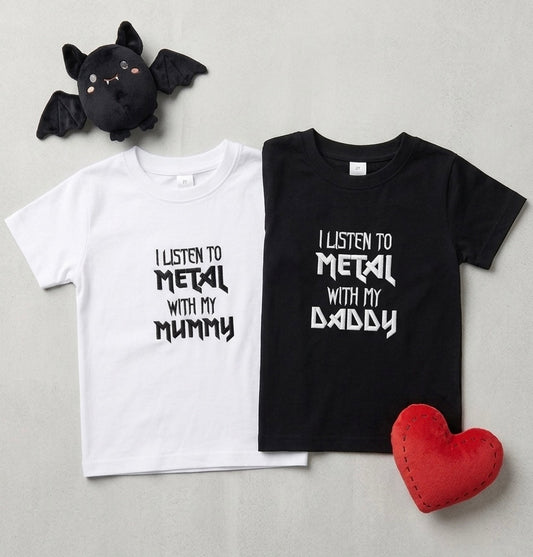 Two kids' t-shirts, one white and one black, laid flat on a light gray background. The white shirt has black embroidered text reading 'I LISTEN TO METAL WITH MY MUMMY' and the black shirt has white text reading 'I LISTEN TO METAL WITH MY DADDY'.