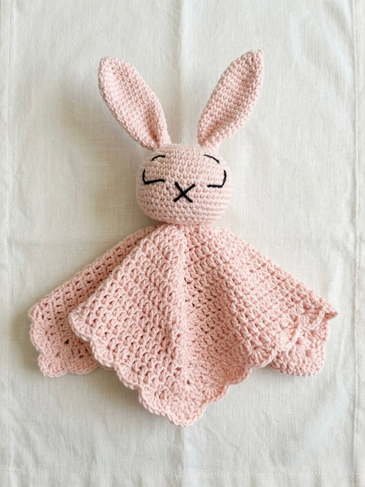 Pink crocheted bunny comfort blanket on a white background