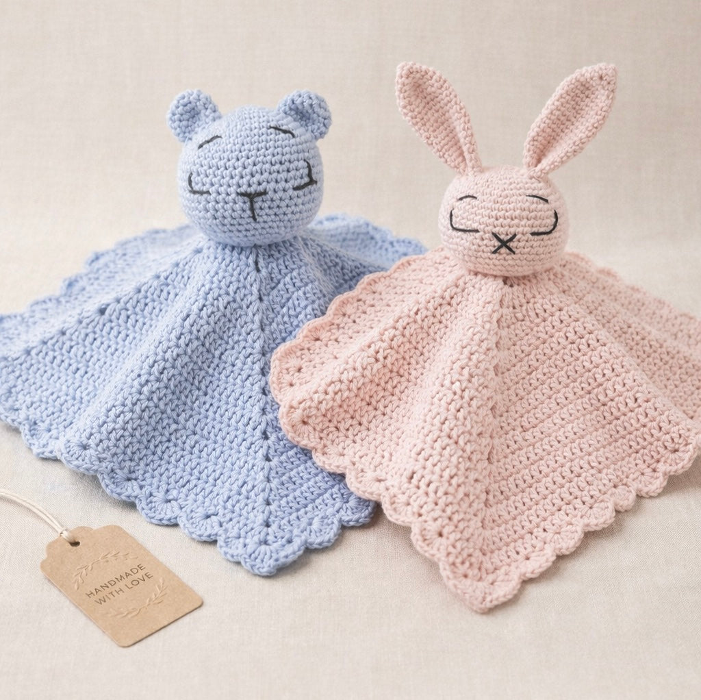 Two crocheted comfort blankets, one blue and one pink, on a light background.